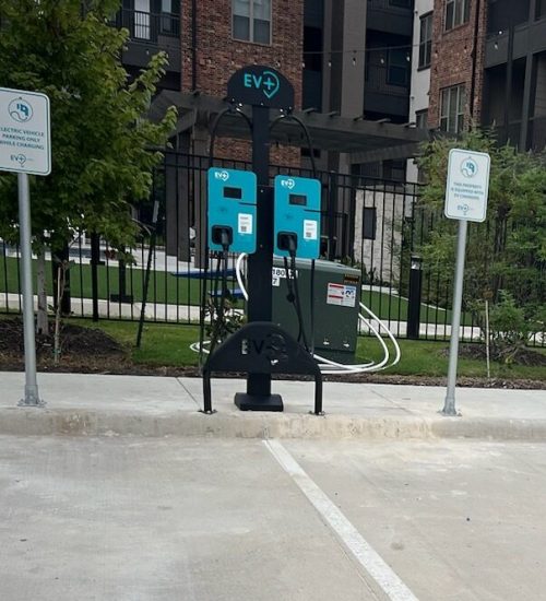 Multiple electric vehicle charging stations lined up in a parking area, featuring modern design and clear charging indicators.