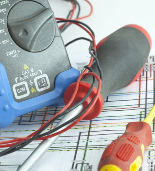 Electric testing equipment displayed on a workbench, including multimeters and tools for measuring electrical parameters.