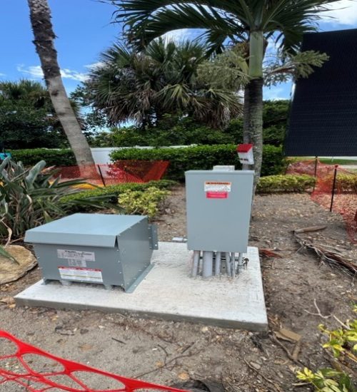 A row of electric transformers in a substation, highlighting their structure and connection to power lines for energy distribution.