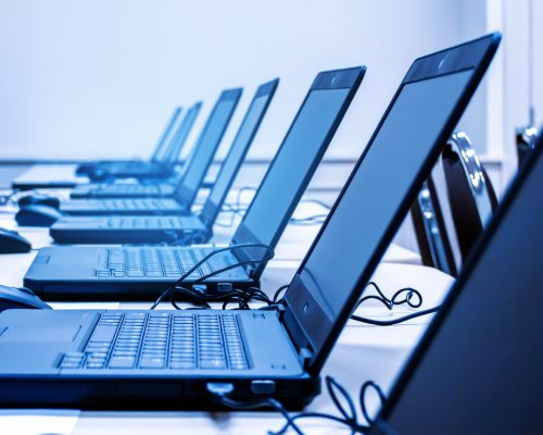 Several laptops lined up on a desk.