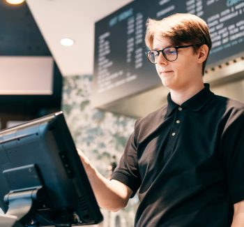 A close-up of a modern point-of-sale system on a counter, featuring a touchscreen.