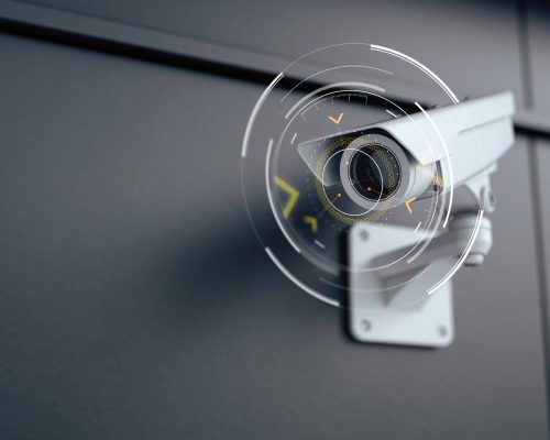 A close-up of a CCTV camera mounted on a wall, monitoring a well-lit area, emphasizing security and surveillance.