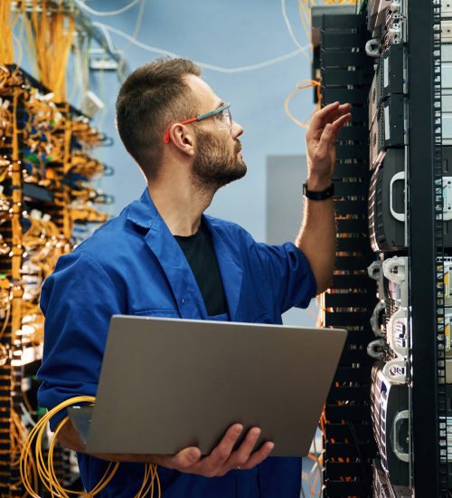 A network engineer working on a laptop, analyzing network configurations in a modern office setting with tech equipment around.